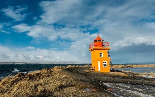 Visite l'Islande : Phare jaune et rouge en bord de mer