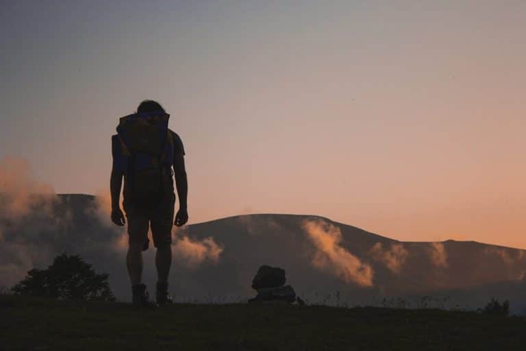 Autotour & randonnée Oman : Un randonneur en excursion se trouve debout face aux montagnes admirant le paysage.