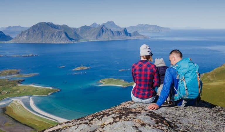 Randonnée îles Lofoten : Famille assise au bord d'une falaise face à la mer