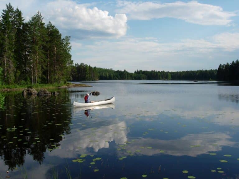 Voyage au Canada : canoé dans un lac au Québec bordé d'une forêt Akaoka