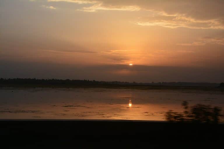 Trek en Inde à Padum : un coucher de soleil sur un lac et une forêt dense à l'horizon Akaoka