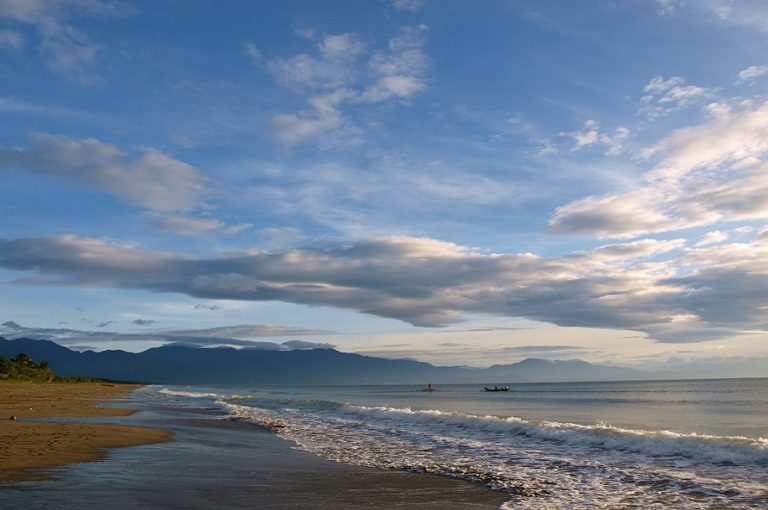 Voyage aux Philippines sur l'île Lucon : la plage, une barque et des montagnes au loin Akaoka