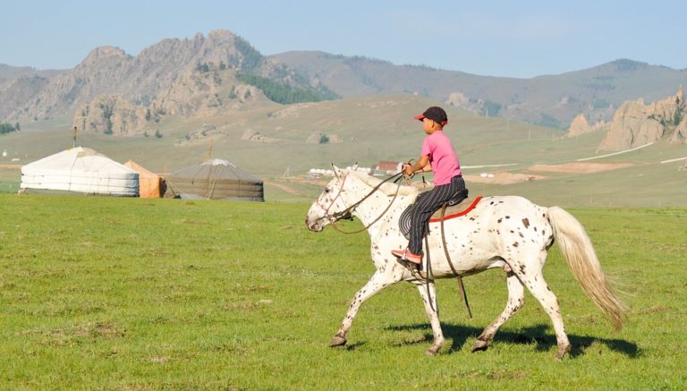 Randonnée en Mongolie à cheval dans une vallée entourée de montagnes Akaoka