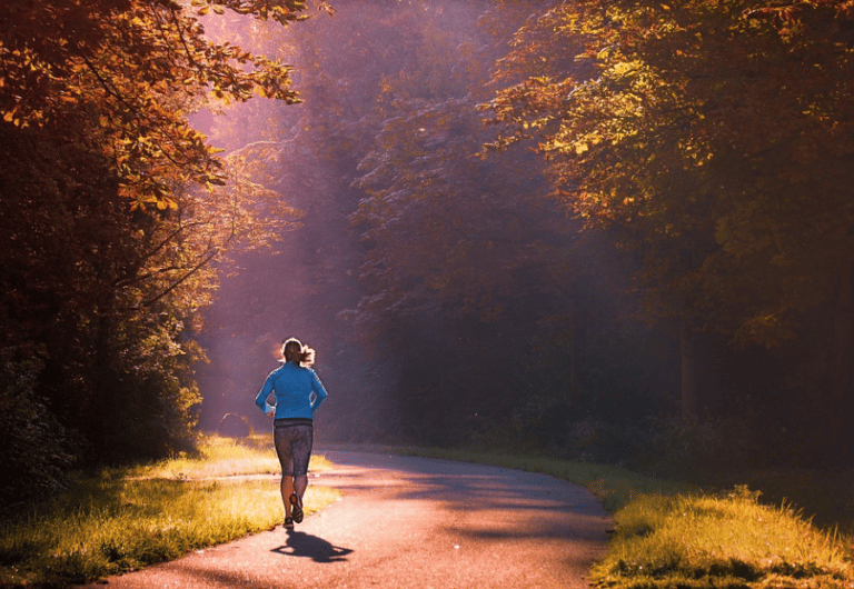 Une femme qui marche dans un passage d’arbre aux feuilles rouge et orange,randonnée bord de mer