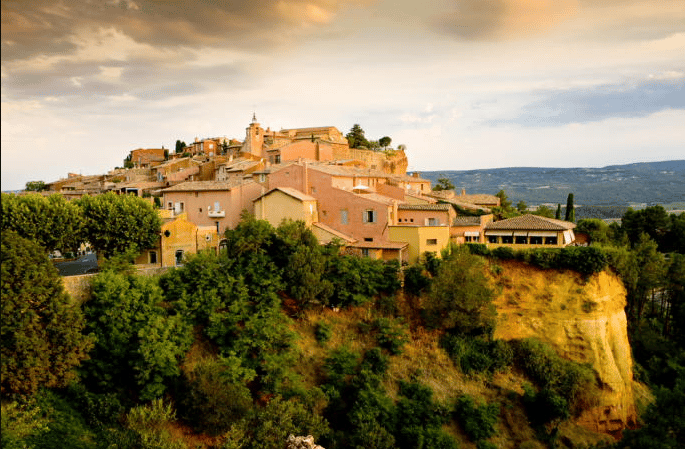 Un petit village sur une colline entoure d’arbres, parc naturel du Luberon randonnée