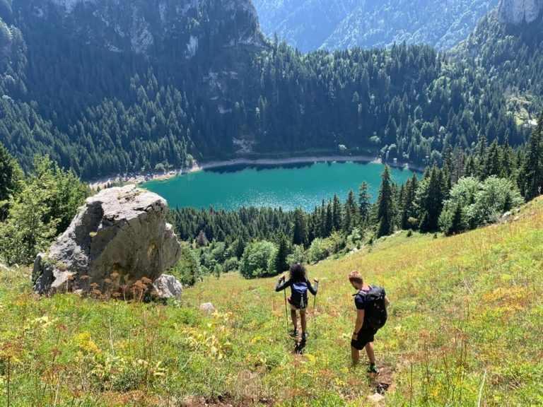 Rando suisse couple marchant en direction du lac bleu vue sur un rocher et les arbres du Val d’Hérens