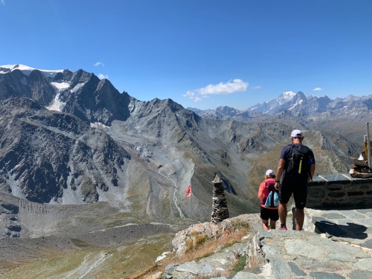 Trekking Suisse : Couple qui marche dans la vallée du valais avec une impressionnante vue sur les montagnes