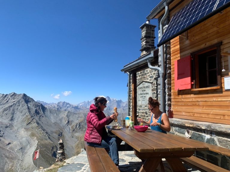 Trekking Suisse : Femmes prenant leur déjeuner dans une cabane avec une vue sur les montagnes